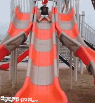 A Little Boy Wearing A Red Hat Is Sliding Down An Orange Slide GIF