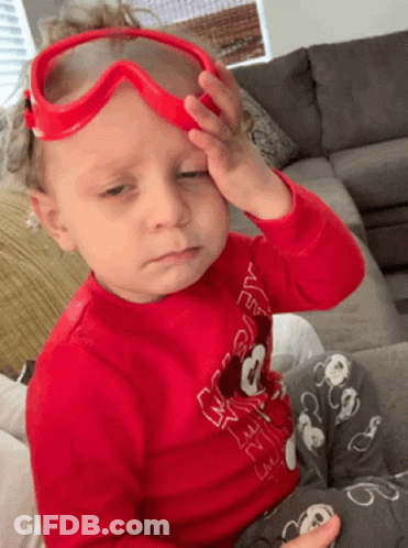 A Little Boy Wearing A Red Shirt With Mickey Mouse On It Is Rubbing His Forehead GIF