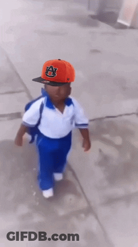 A Little Boy Wearing An Auburn Hat Is Running Down The Street GIF