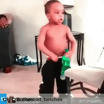 A Little Boy Without A Shirt Is Holding A Green Bottle Of Soda . GIF