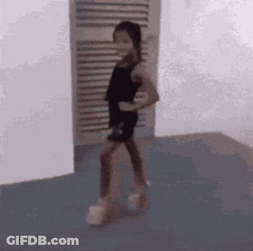 A Little Girl In A Black Dress Is Standing In A Room . GIF