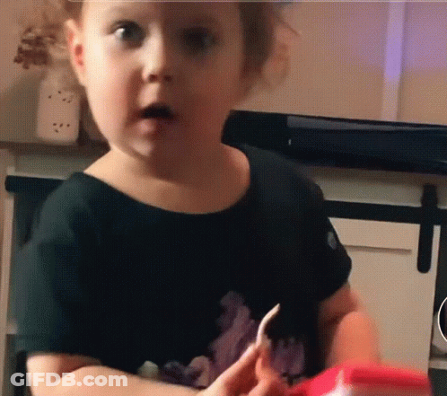 A Little Girl In A Black Shirt Is Holding A Piece Of Paper GIF