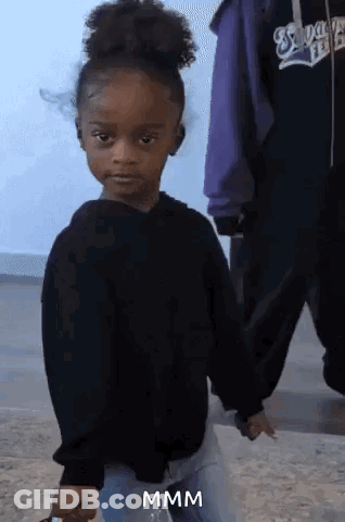 A Little Girl In A Black Sweater Is Holding Someone 'S Hand And Making A Funny Face .. GIF