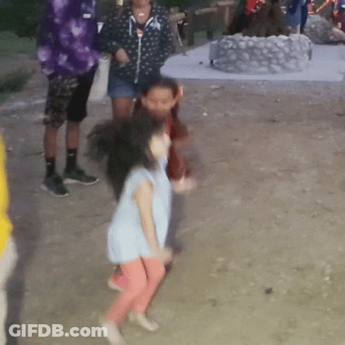 A Little Girl In A Blue Shirt And Pink Pants Is Dancing In The Dirt GIF
