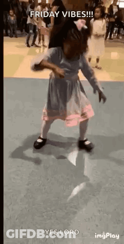A Little Girl In A Dress Is Dancing On A Floor In A Room . GIF