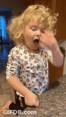 A Little Girl In A Leopard Print Shirt Is Sitting On A Counter With Her Mouth Open GIF