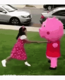 A Little Girl In A Pink Dress Is Playing With A Pink Pig Mascot . GIF