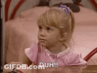 A Little Girl In A Pink Dress Is Sitting At A Table With A Person Holding Her Hand . GIF
