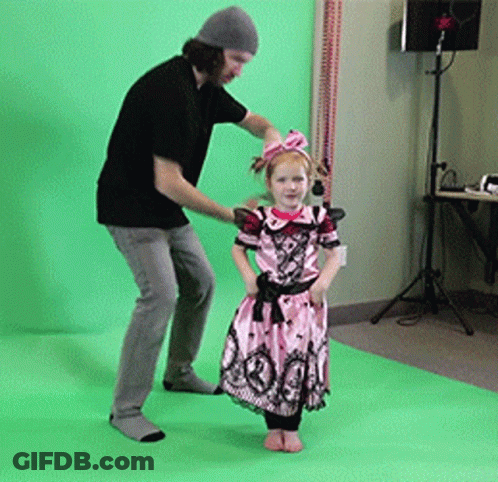 A Little Girl In A Pink Dress Is Standing Next To A Man GIF