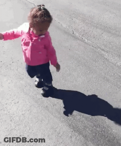 A Little Girl In A Pink Jacket Is Running Down A Road . GIF