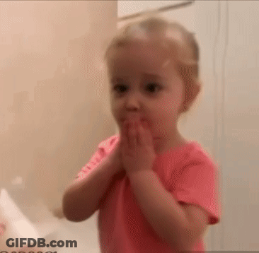 A Little Girl In A Pink Shirt Is Covering Her Mouth With Her Hands In A Bathroom . GIF
