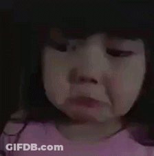 A Little Girl In A Pink Shirt Is Crying And Making A Sad Face . GIF