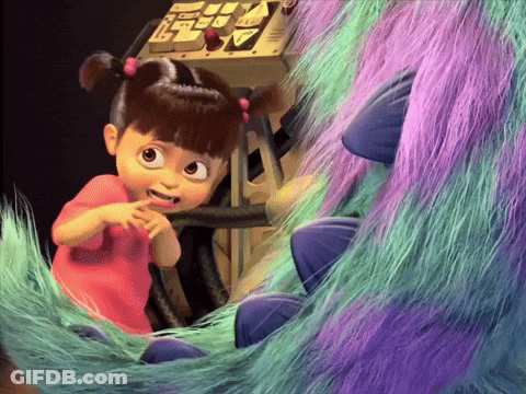 A Little Girl In A Pink Shirt Is Sitting Next To A Purple And Green Monster GIF