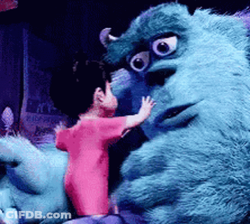 A Little Girl In A Pink Shirt Is Standing Next To A Blue Monster GIF