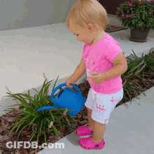 A Little Girl In A Pink Shirt Is Watering Plants GIF