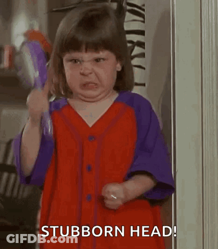 A Little Girl In A Red And Purple Dress Is Holding A Brush And Making A Funny Face . GIF
