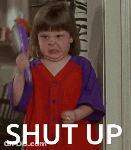 A Little Girl In A Red And Purple Shirt Is Holding A Brush And Making A Face With The Words Shut Up Behind Her GIF