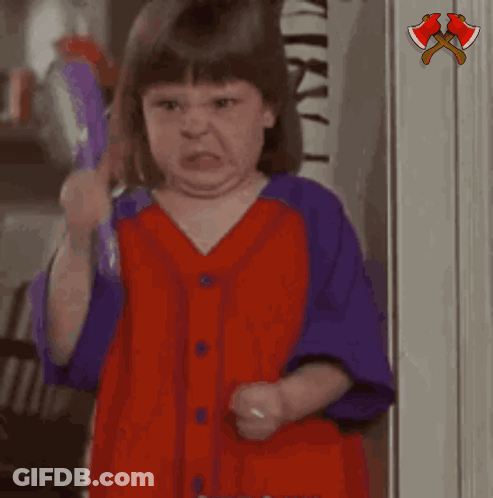 A Little Girl In A Red And Purple Shirt Is Holding A Purple Object And Saying Hushh GIF