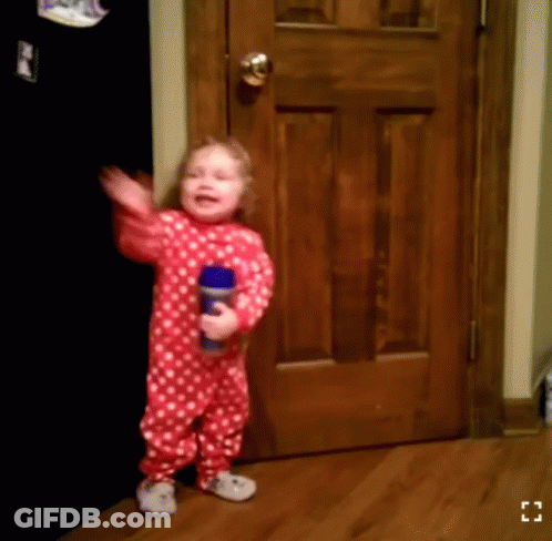 A Little Girl In A Red And White Polka Dot Pajamas Is Holding A Blue Bottle GIF