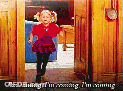 A Little Girl In A Red Shirt Is Running Through A Doorway And Says I 'M Coming I 'M Coming GIF