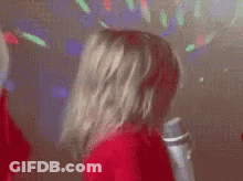 A Little Girl In A Red Sweater Is Holding A Microphone In Her Hand . GIF