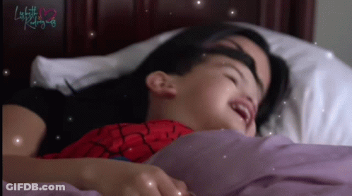 A Little Girl In A Spiderman Costume Is Laying In Bed With Her Mother GIF