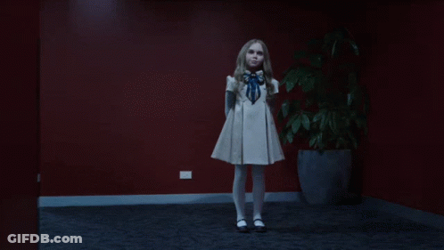A Little Girl In A White Dress Is Dancing In Front Of A Potted Plant GIF