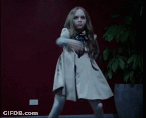 A Little Girl In A White Dress Is Dancing In Front Of A Potted Plant GIF
