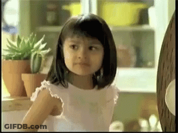 A Little Girl In A White Dress Is Standing In Front Of Potted Plants GIF