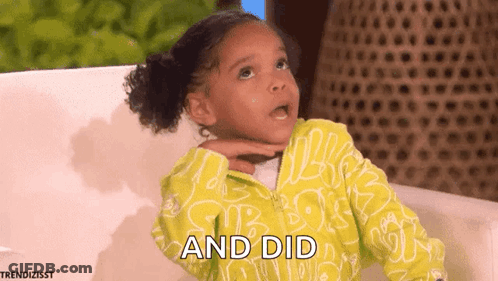 A Little Girl In A Yellow Jacket Is Sitting On A Couch And Making A Funny Face . GIF