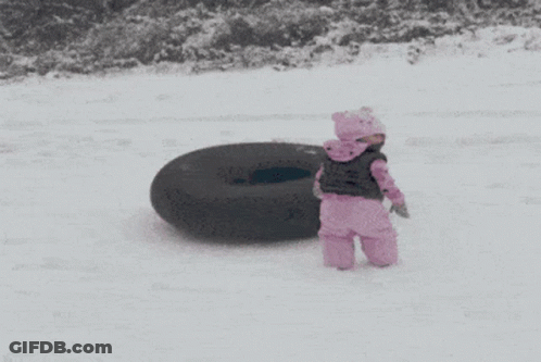 A Little Girl In Pink Standing Next To A Black Tire GIF