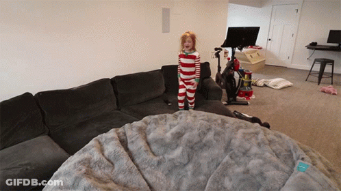A Little Girl In Striped Pajamas Stands On A Couch GIF