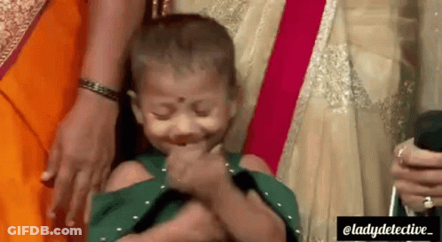 A Little Girl Is Being Held By A Woman And Making A Funny Face . GIF