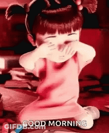 A Little Girl Is Covering Her Face With Her Hands And The Words `` Good Morning '' Written On The Bottom . GIF