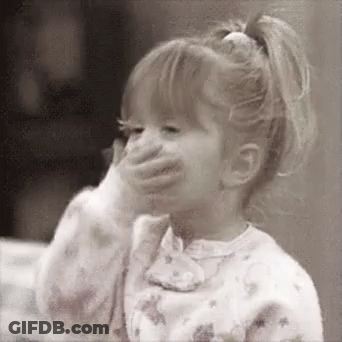A Little Girl Is Covering Her Mouth With Her Hand And Smiling . GIF