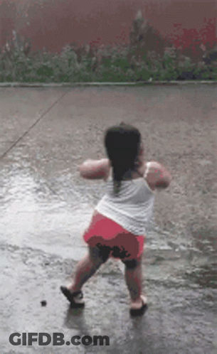 A Little Girl Is Dancing In A Puddle Of Water GIF