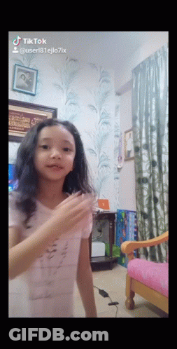A Little Girl Is Dancing In A Room With A Pink Chair And A Picture On The Wall That Says Tiktok GIF