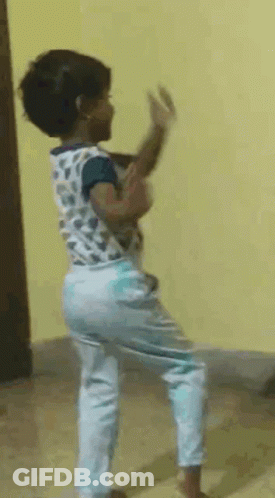 A Little Girl Is Dancing In A Room With A Yellow Wall Behind Her . GIF