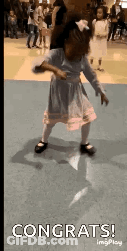 A Little Girl Is Dancing In A Room With The Words `` Congrats '' Written On The Bottom . GIF