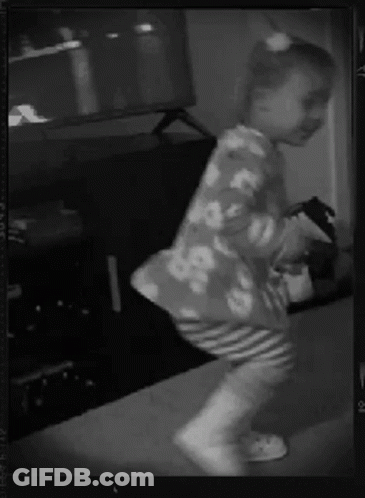 A Little Girl Is Dancing In Front Of A Tv In A Black And White Photo GIF