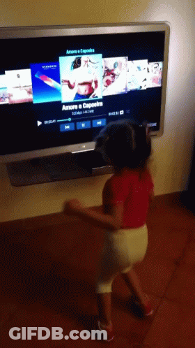 A Little Girl Is Dancing In Front Of A TV Screen That Says Amore Capoeira GIF