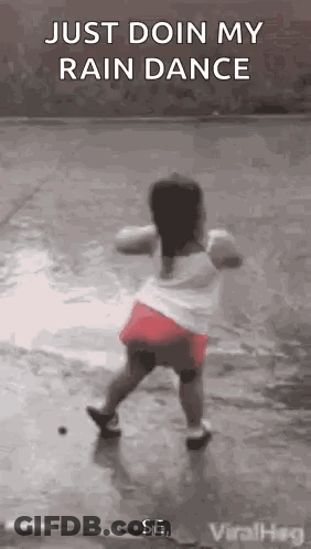 A Little Girl Is Dancing In The Rain On A Wet Sidewalk . GIF