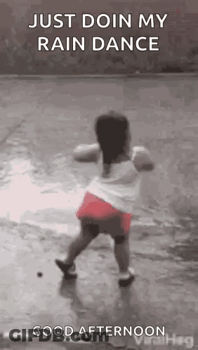 A Little Girl Is Dancing In The Rain On A Wet Sidewalk . GIF