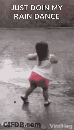 A Little Girl Is Dancing In The Rain On The Sidewalk . GIF