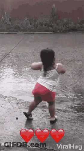 A Little Girl Is Dancing In The Rain With Red Hearts . GIF