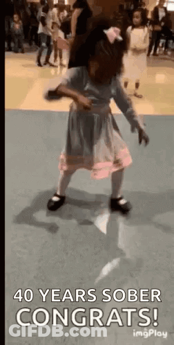 A Little Girl Is Dancing On A Dance Floor With The Words `` 40 Years Sober Congrats '' . GIF