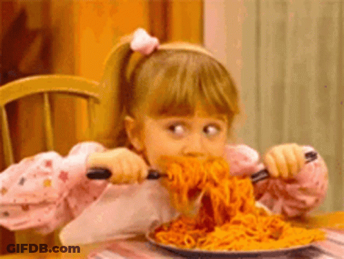 A Little Girl Is Eating Spaghetti With A Fork And Spoon . GIF