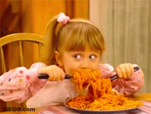 A Little Girl Is Eating Spaghetti With A Fork And Spoon . GIF