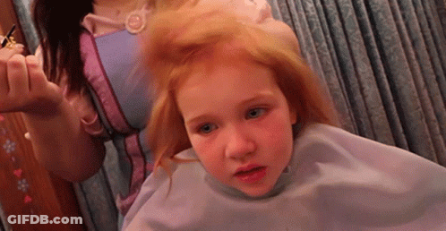 A Little Girl Is Getting Her Hair Cut By A Woman In A Pink Dress GIF