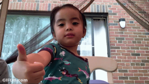 A Little Girl Is Giving A Thumbs Up Sign GIF